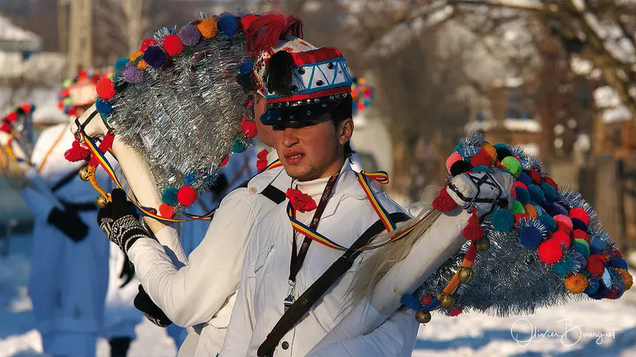 Jeune homme en costume traditionnel à pompons colorés, dans la neige, Roumanie